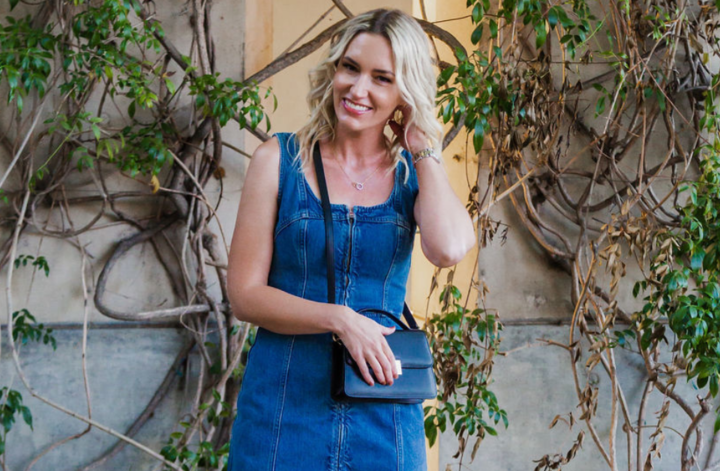 Jaquelyn Wahidi wears a denim dress with a black crossbody bag and mixed metal jewelry.