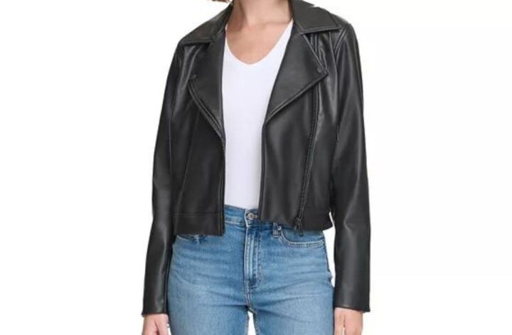 Model wears a lightweight jacket for fall 2023. It's a black faux leather motor jacket paired with a white tee and jeans.