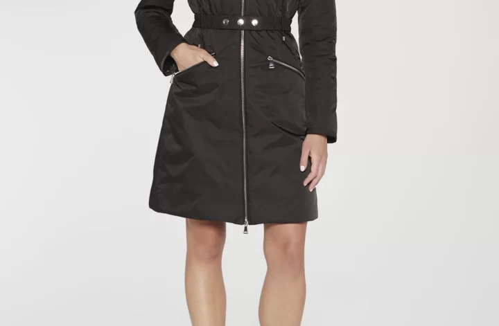 A stylish, black raincoat by luxury brand Moncler is modeled against a grey background.