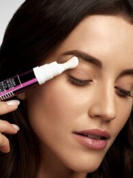 Brunette model uses sisley eye fluid, a luxury skin care product